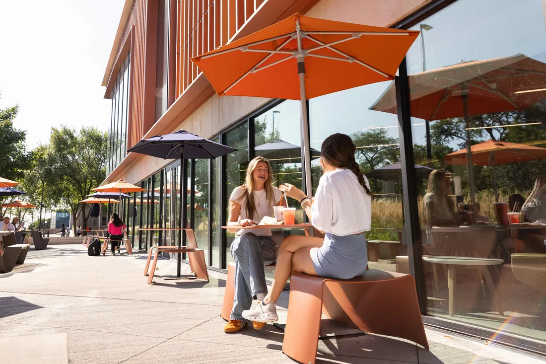 Two students sitting outside talking.