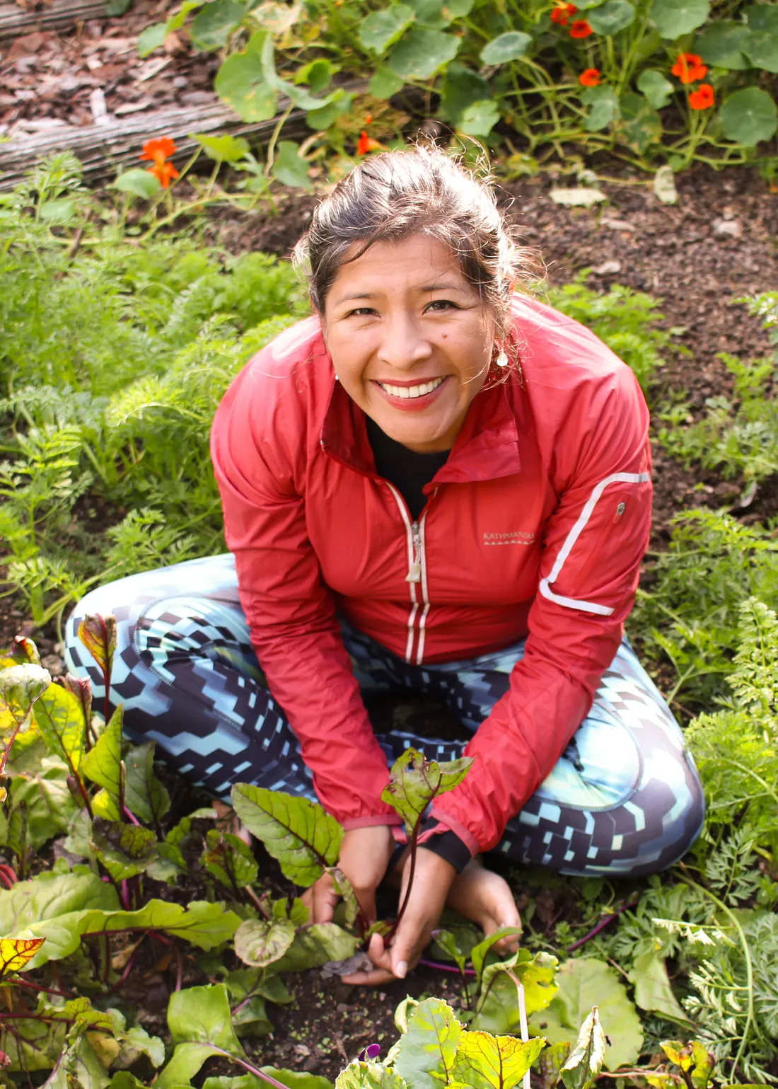 Mariaelena Huambachano sitting in a garden holding plants.