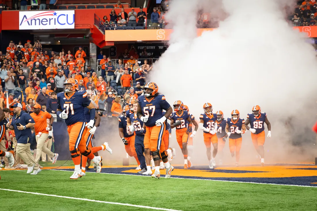 The Syracuse University football team running on the field.